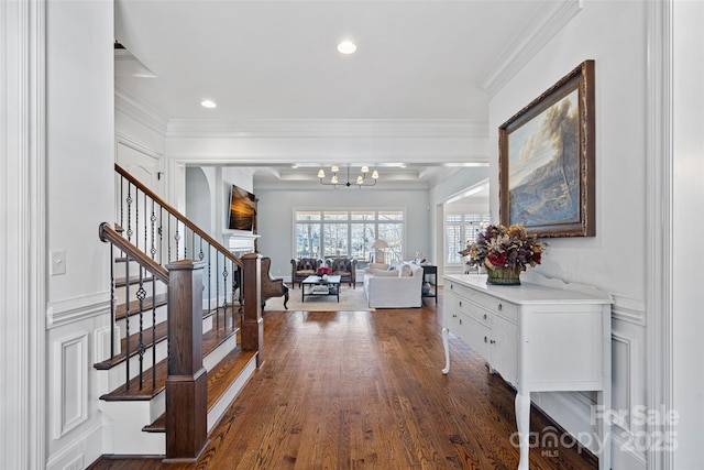 foyer entrance with crown molding, dark hardwood / wood-style floors, and an inviting chandelier