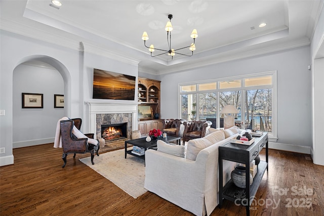 living room featuring dark wood-type flooring, a raised ceiling, and a chandelier