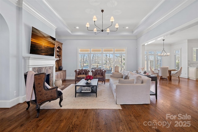 living room featuring an inviting chandelier, hardwood / wood-style floors, ornamental molding, and a raised ceiling