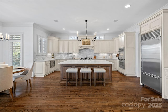 kitchen featuring built in appliances, hanging light fixtures, dark wood-type flooring, and a kitchen island