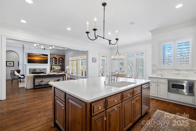 kitchen with appliances with stainless steel finishes, pendant lighting, an island with sink, sink, and an inviting chandelier