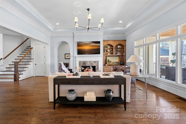 living room featuring a raised ceiling, crown molding, dark hardwood / wood-style floors, and a chandelier