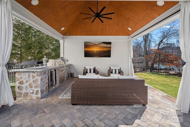 view of patio featuring ceiling fan, an outdoor kitchen, an outdoor hangout area, and grilling area