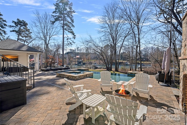 view of patio featuring a swimming pool with hot tub and an outdoor fire pit