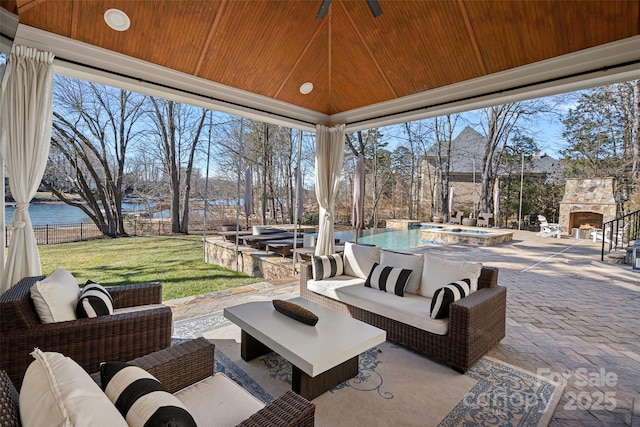 view of patio featuring a water view, an outdoor living space with a fireplace, and a fenced in pool