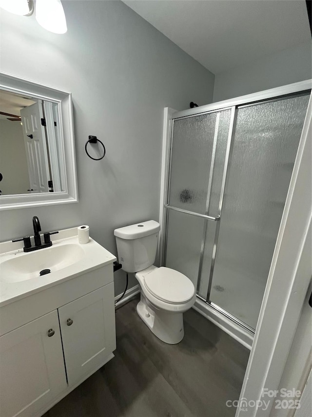 bathroom with vanity, hardwood / wood-style floors, a shower with door, and toilet