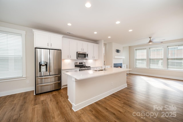 kitchen with stainless steel appliances, an island with sink, sink, and white cabinets