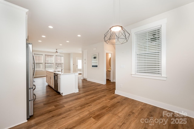 kitchen with dark hardwood / wood-style flooring, sink, decorative light fixtures, and an island with sink