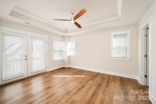 unfurnished bedroom with access to exterior, a tray ceiling, and hardwood / wood-style flooring