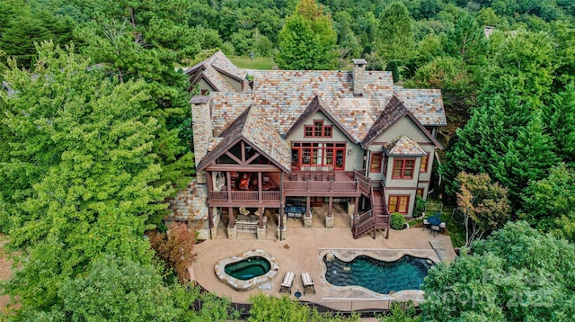 back of house featuring a patio, a chimney, a high end roof, and an in ground hot tub