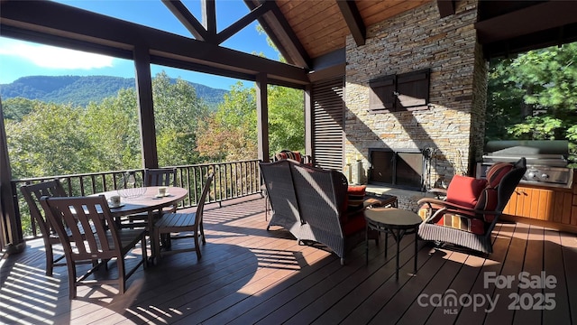 wooden terrace with outdoor dining area, area for grilling, and a mountain view