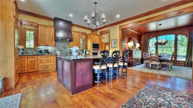 kitchen with light wood-style flooring, built in microwave, a notable chandelier, and oven