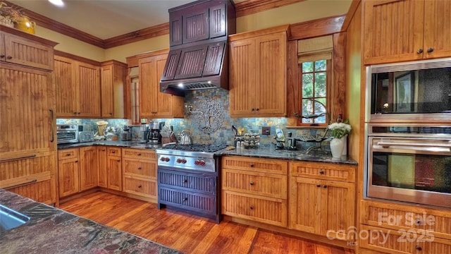 kitchen featuring light wood finished floors, tasteful backsplash, custom exhaust hood, and built in microwave