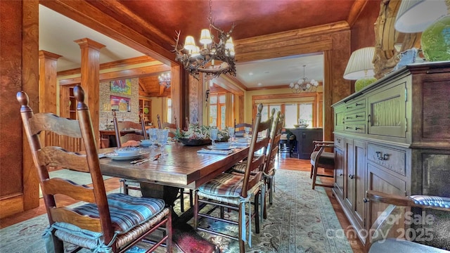 dining room featuring wood finished floors, beam ceiling, an inviting chandelier, decorative columns, and crown molding