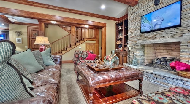 carpeted living room with stairs, built in shelves, a stone fireplace, and beam ceiling