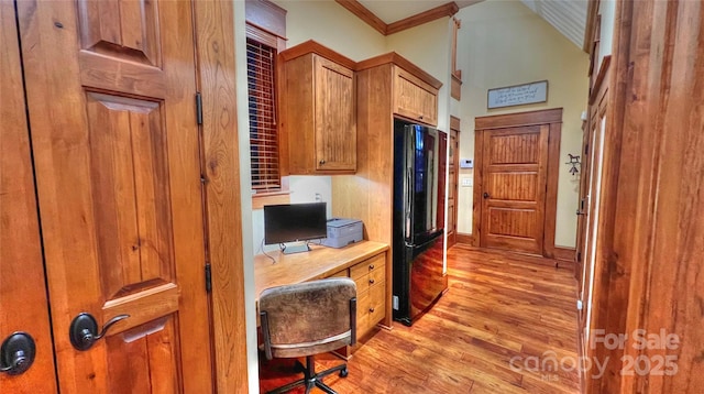 interior space featuring baseboards, light wood-style flooring, ornamental molding, and built in desk