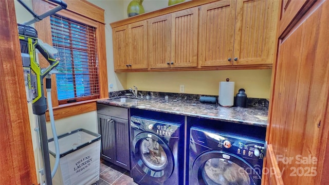 clothes washing area featuring cabinet space, a sink, dark tile patterned floors, and washing machine and clothes dryer