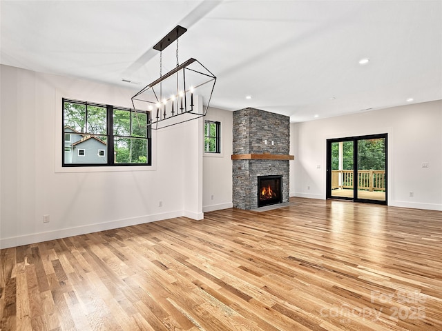 unfurnished living room featuring a stone fireplace and light hardwood / wood-style flooring