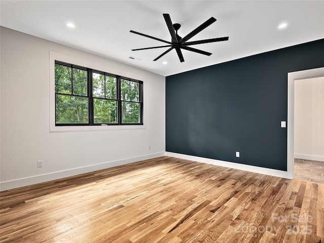 empty room with ceiling fan and light hardwood / wood-style floors