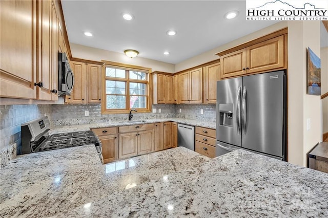 kitchen featuring sink, backsplash, stainless steel appliances, and light stone countertops