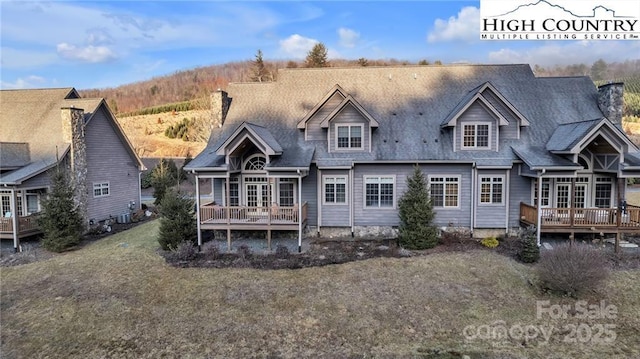 rear view of house with a wooden deck and a lawn