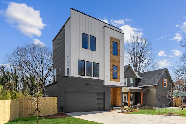 contemporary home with board and batten siding, a garage, fence, and concrete driveway