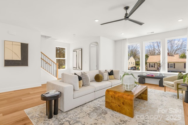 living area featuring visible vents, stairway, baseboards, and wood finished floors