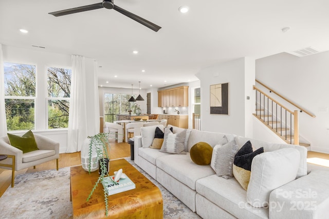 living room with visible vents, a ceiling fan, stairway, light wood-style floors, and recessed lighting