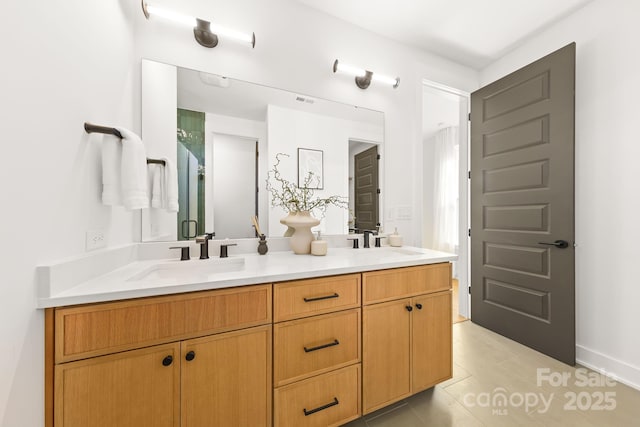 full bathroom with double vanity, an enclosed shower, a sink, and tile patterned floors