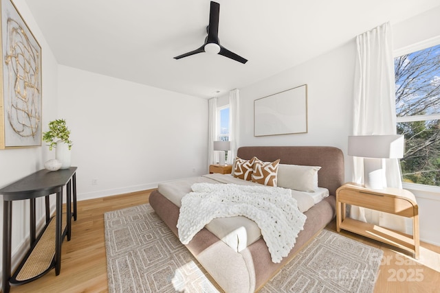 bedroom with light wood-style floors, ceiling fan, and baseboards