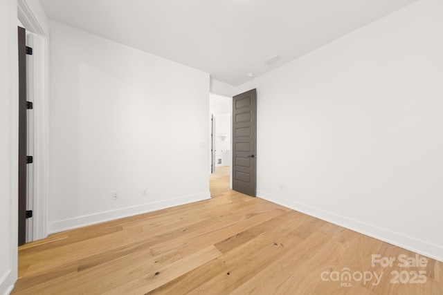 empty room featuring light wood-type flooring, visible vents, and baseboards