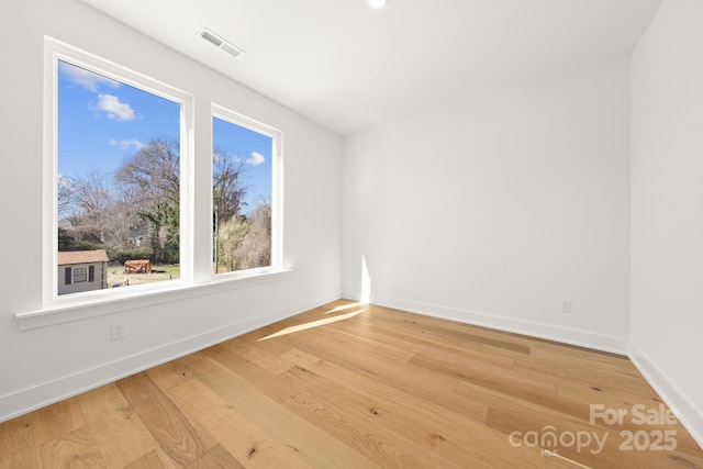 empty room with light wood-style floors, visible vents, and baseboards