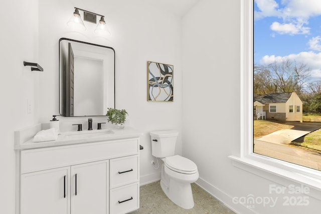 half bathroom featuring baseboards, vanity, and toilet