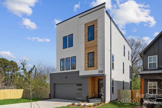 modern home with a garage, board and batten siding, fence, and concrete driveway