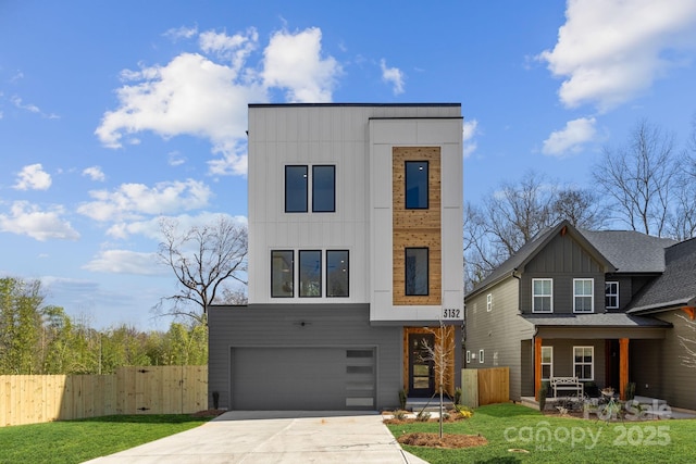 modern home featuring concrete driveway, board and batten siding, a front yard, fence, and a garage