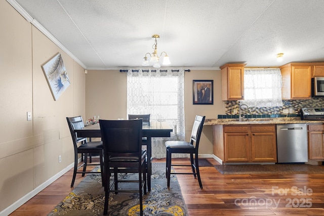 dining room with crown molding, dark hardwood / wood-style flooring, a chandelier, and sink