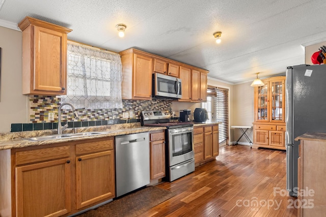 kitchen with sink, stainless steel appliances, dark hardwood / wood-style floors, tasteful backsplash, and ornamental molding