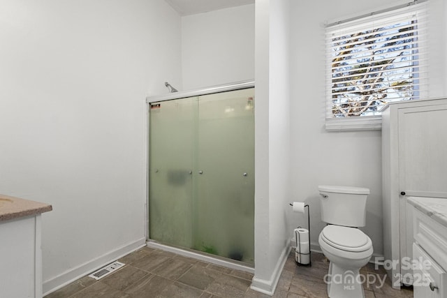 bathroom with vanity, a shower with shower door, and toilet