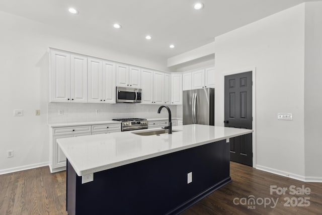 kitchen with white cabinetry, appliances with stainless steel finishes, sink, and a kitchen island with sink