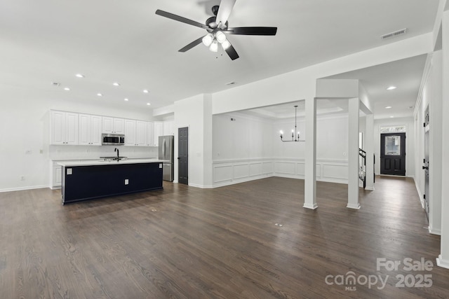 unfurnished living room featuring sink, ceiling fan with notable chandelier, and dark wood-type flooring