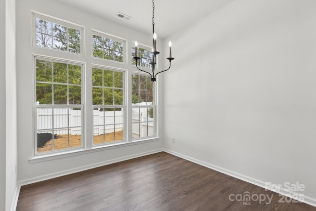 unfurnished dining area with dark wood-type flooring and a notable chandelier