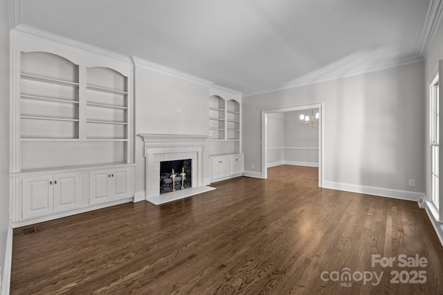 unfurnished living room featuring dark hardwood / wood-style floors, a fireplace, a chandelier, crown molding, and built in shelves