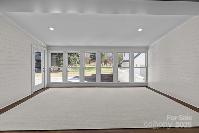 interior space with ornamental molding, lofted ceiling, and wood walls