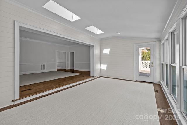 unfurnished room featuring dark wood-type flooring, ornamental molding, and vaulted ceiling with skylight