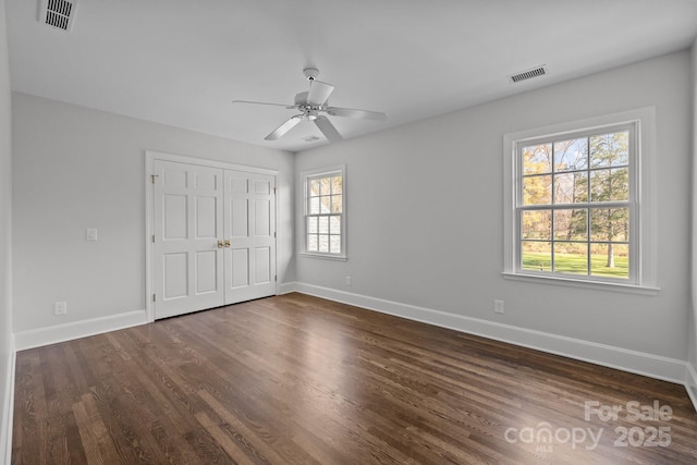 unfurnished bedroom with dark wood-type flooring, ceiling fan, and a closet