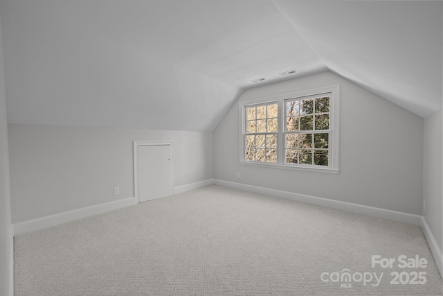 additional living space featuring vaulted ceiling and light colored carpet