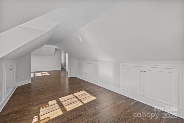 additional living space with dark wood-type flooring and vaulted ceiling