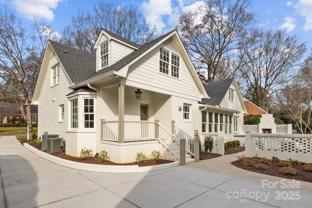 view of front of home with a porch, a fireplace, and central air condition unit