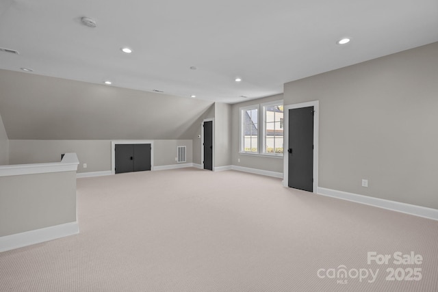 bonus room with vaulted ceiling and light carpet