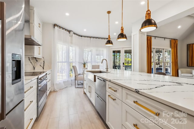 kitchen with light stone countertops, decorative light fixtures, stainless steel appliances, and white cabinets